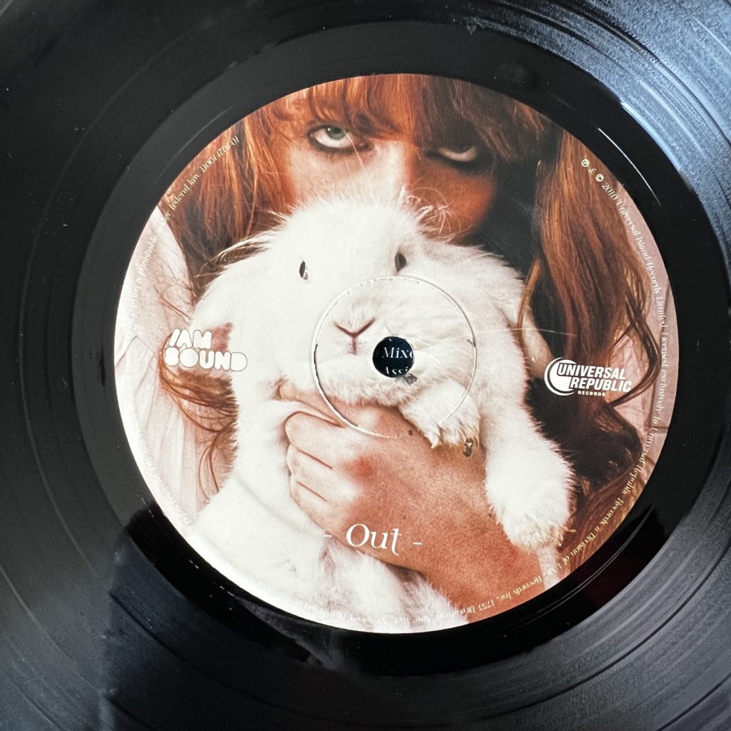 Lungs B Side Label, marked "Out" depicting Florence Welch holding a white rabbit.