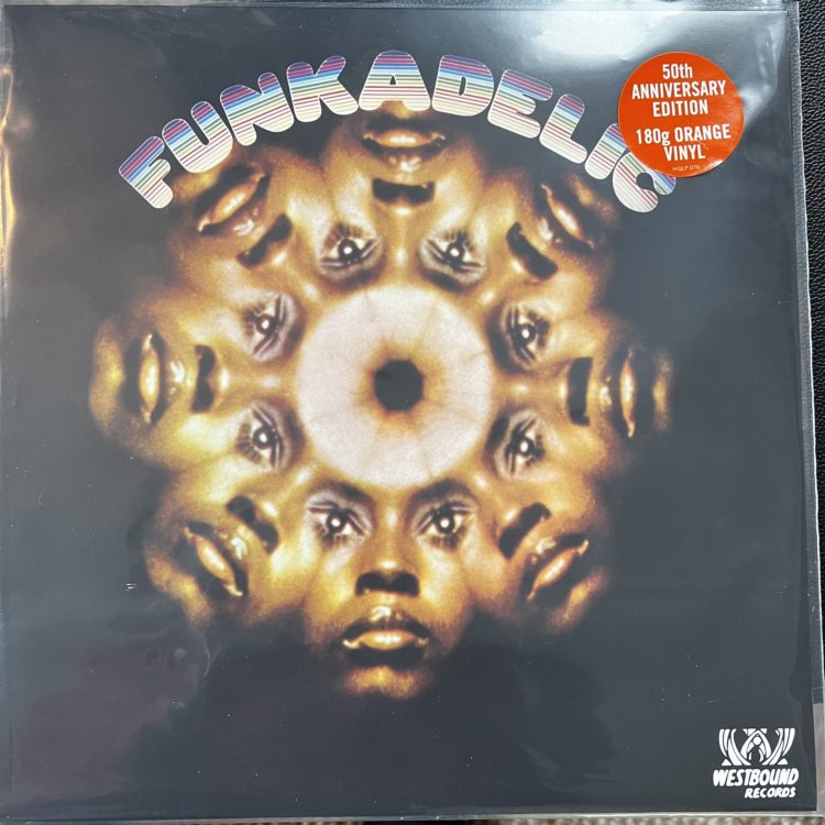 Front cover of the Funkadelic album, "Funkadelic." Under the title is a kaleidoscope-inspired photograph of eight identical faces, joined together in a circle, with the faces overlapping so they each share eyes where the faces meet.
