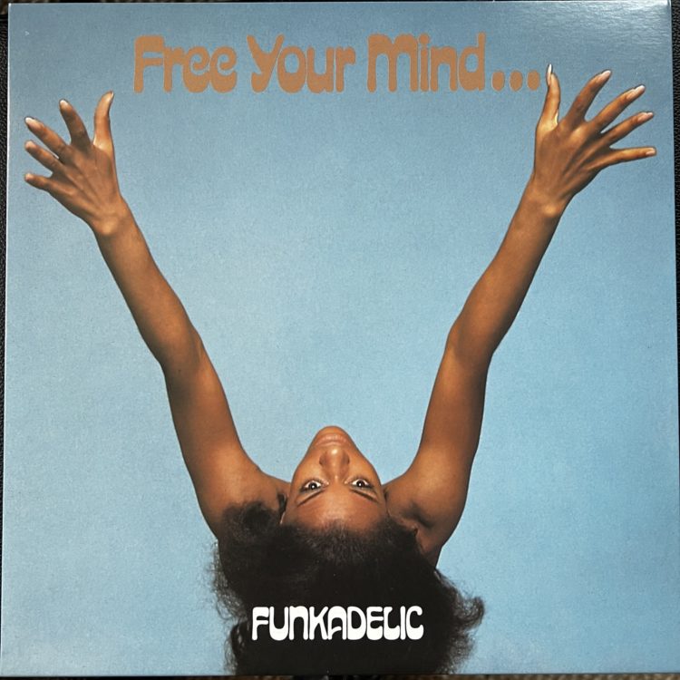 The front cover of the Funkadelic album "Free Your Mind . . . And Your Ass Will Follow." The first half of the title appears above a brownskinned woman, her back to us, arms outstretched, head tipped up and looking skyward.