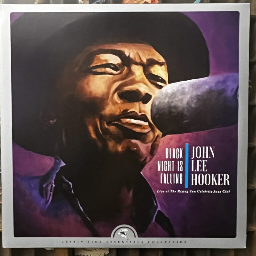 Black Night is Falling front cover – artwork featuring a closeup image of the face of John Lee Hooker singing into a big oblong microphone. He is wearing a dark hat, of which only the brim can be seen, and a shirt with an open collar. His eyes are narrow, perhaps closed, and his lips are pursed. The painting is credited to Canadian designer John Rummen.