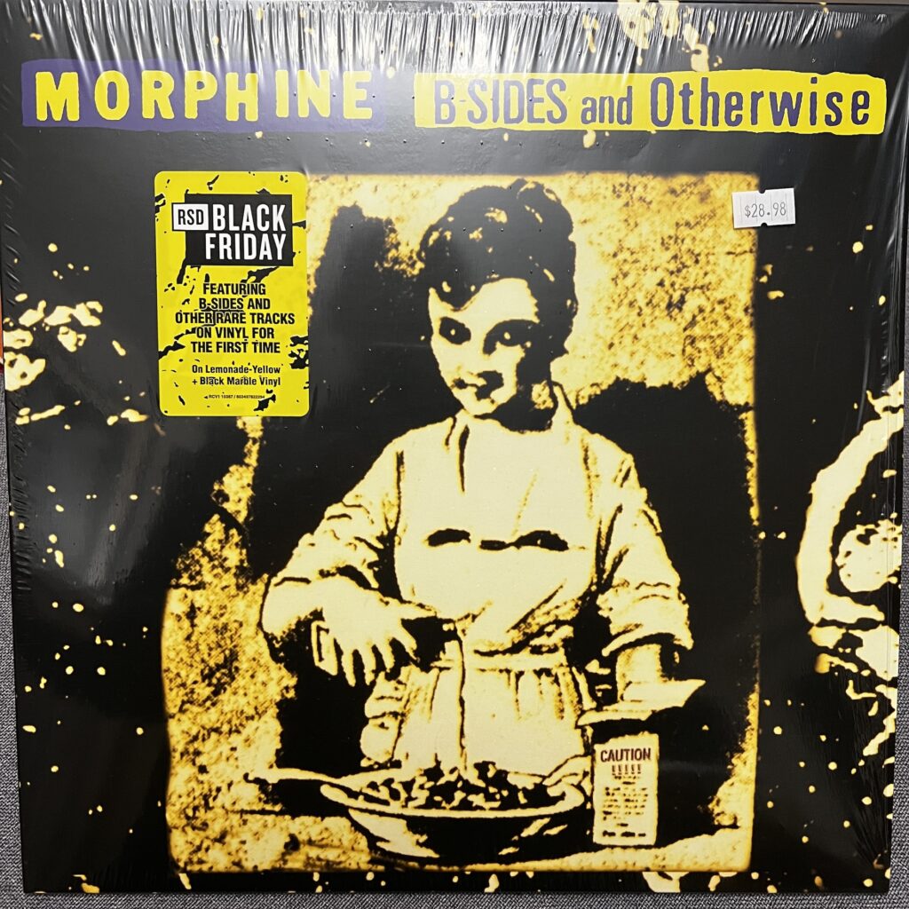  Cover of Morphine B-Sides and Otherwise. Cover image is a degraded photograph or art showing a young person in an old-fashioned dress pouring from a rectangular bottle onto a bowl of food. The box the bottle came from says "Caution!!!!" the overall impression is of an antique image perhaps of poisoning.