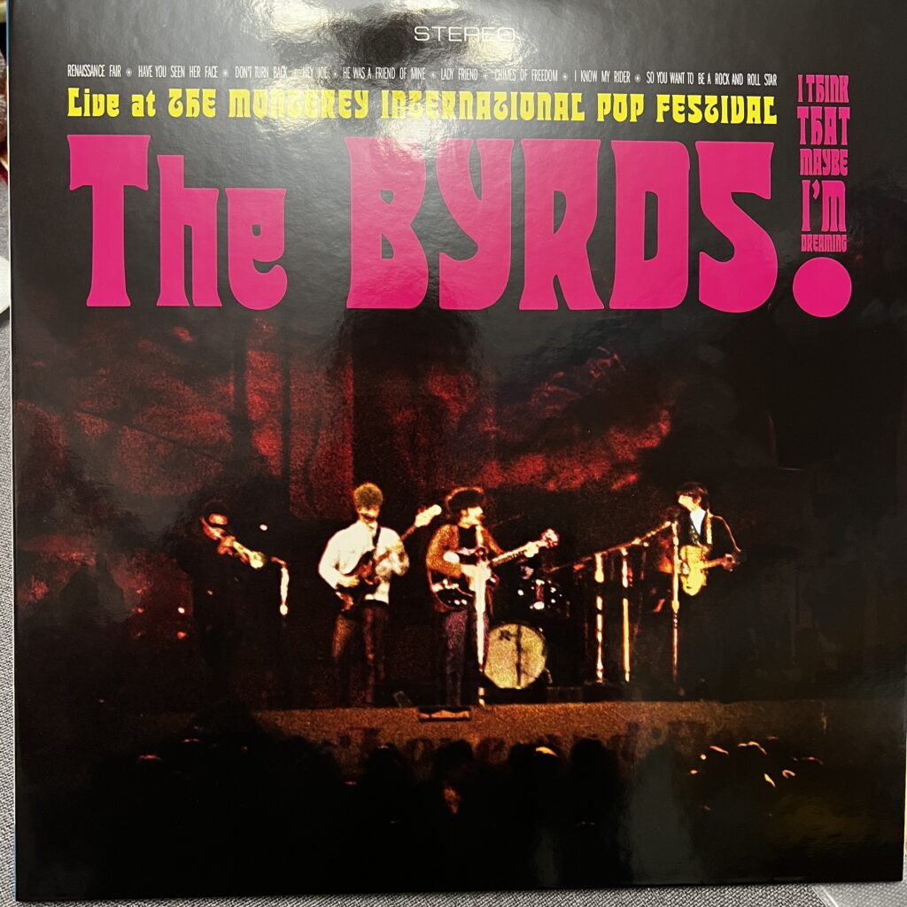 Cover of The Byrds at Monterey International Pop Festival. Type across the top half, a dark and not very clear image of the band below, with a horn player, bass player, two guitarists and drummer visible.