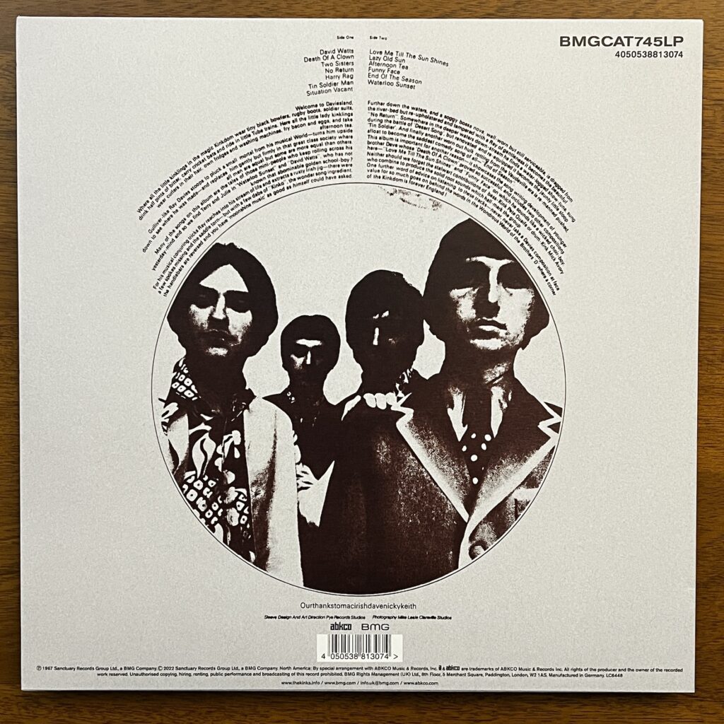 Back cover of Something Else, with track listing and liner notes above a large circular photograph, in highly contrasted black and white, of the band standing, facing the viewer.